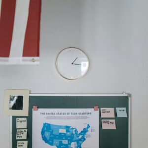 United States tech startup map on chalkboard in office with clock and American flag.